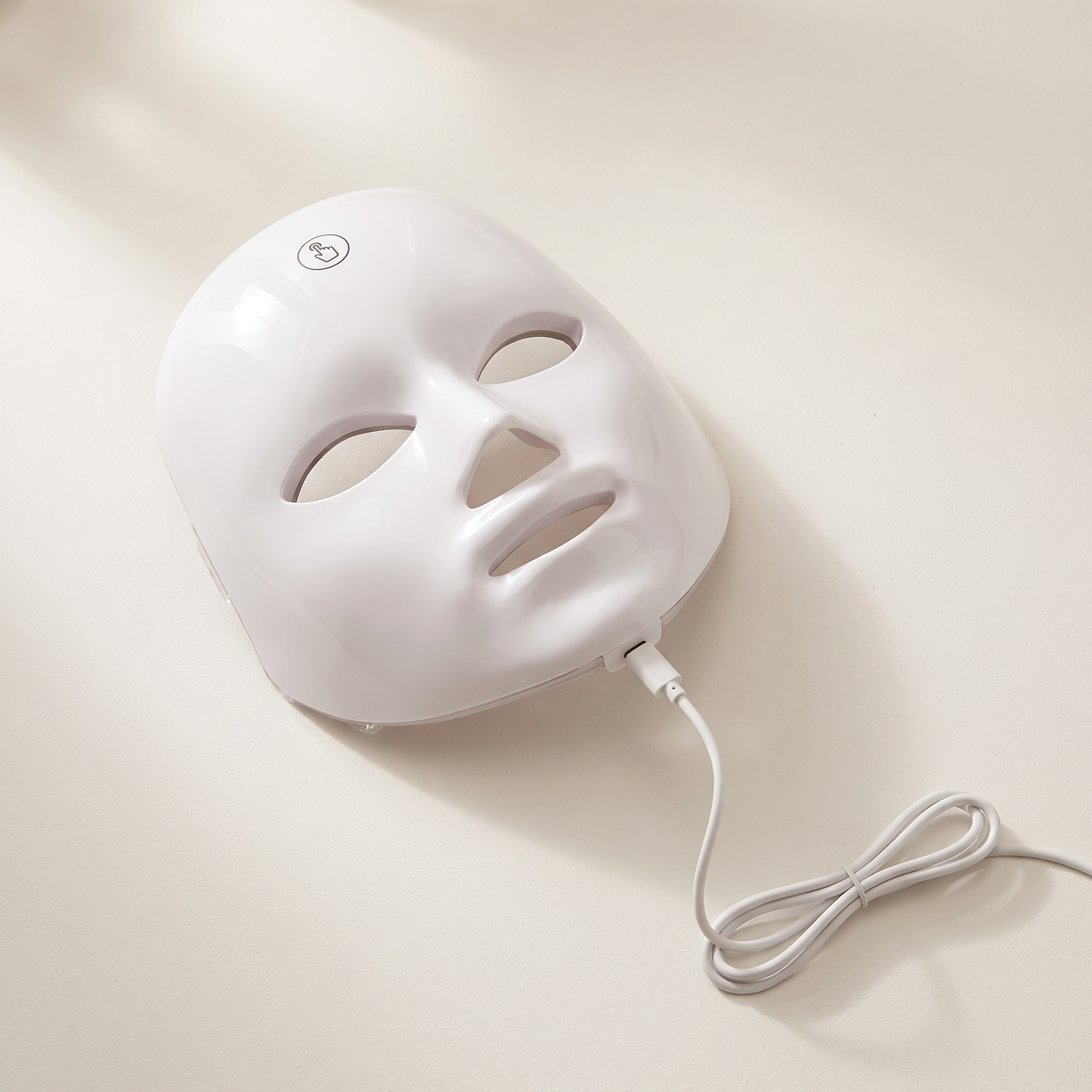 The mask on a plain surface with its USB-C charging cable, no wall outlet